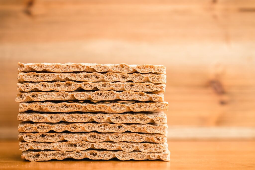 A neatly stacked pile of crispbread crackers against a wooden background.