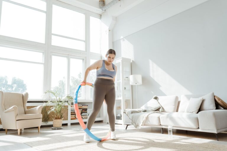 A woman engages in a hula hoop workout in a bright, modern living room, promoting wellness and healthy living.