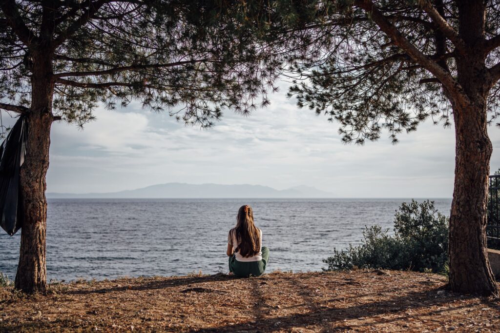 A woman enjoys a peaceful moment by the sea in Ozdere, Turkey, with a scenic view of nature and water.