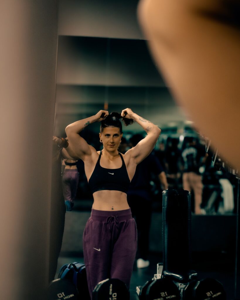 Focused woman tying her hair in a gym, getting ready for an intense workout session.