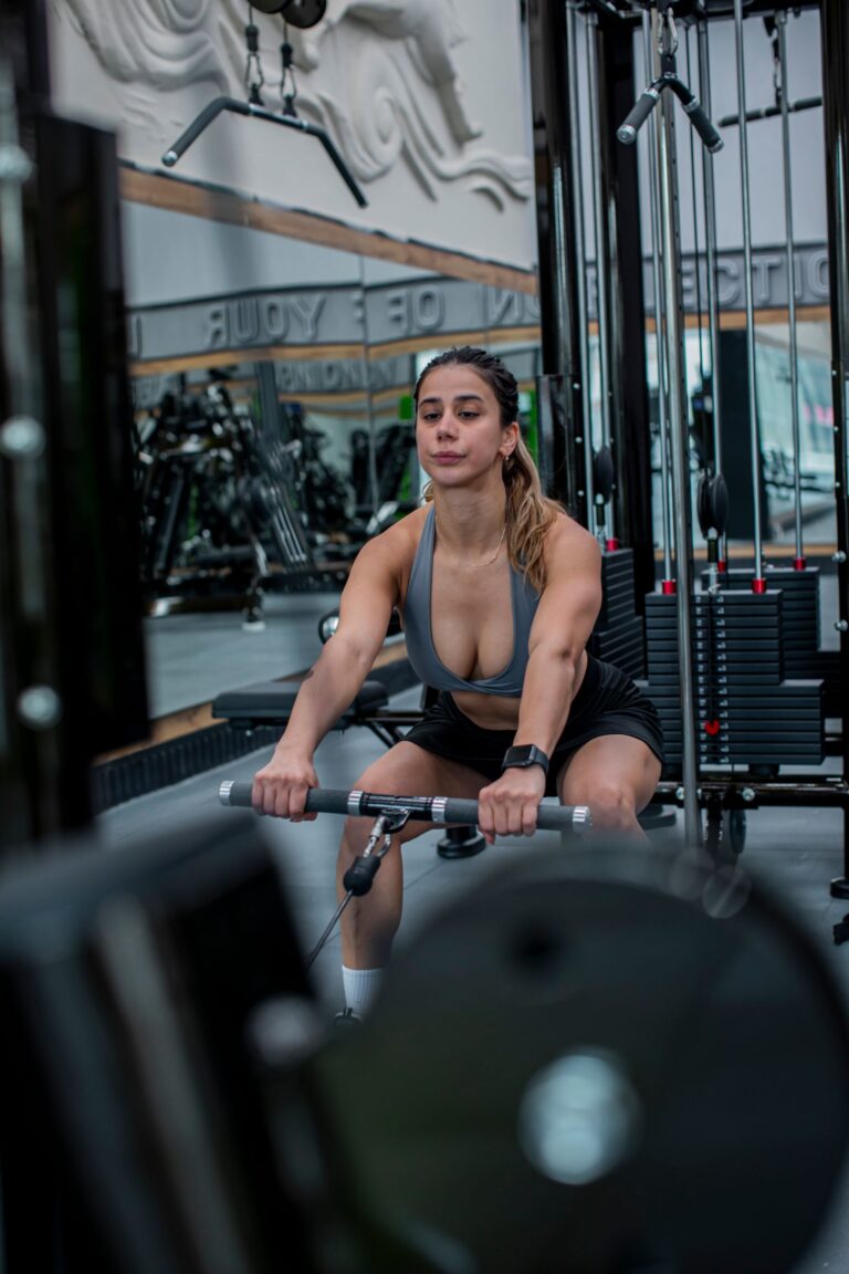 Focused woman working out on a rowing machine in a modern gym setting. Strength and determination.