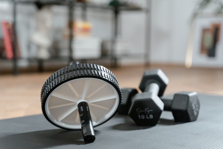 Ab roller and dumbbells on yoga mat, perfect for a home workout routine and healthy lifestyle.