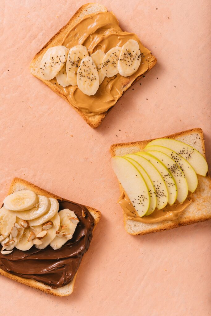 Aerial view of toast with peanut butter, banana, apple, and chocolate spreads. Perfect breakfast.