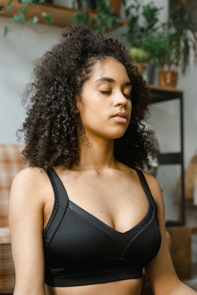 African American woman meditating indoors with closed eyes, capturing a serene lifestyle moment.