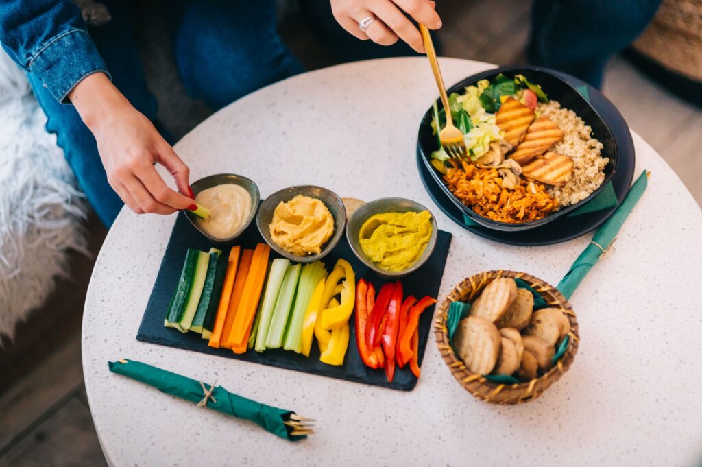 Colorful display of healthy snacks with salad, hummus, and veggies on a table.