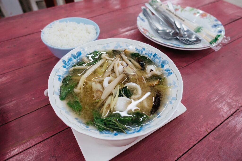 Delicious seafood miso soup with fresh vegetables and a side of steamed rice served on a rustic table.