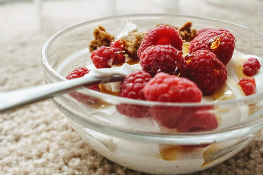 Indulge in creamy yogurt topped with fresh raspberries and sweet honey in a glass bowl.