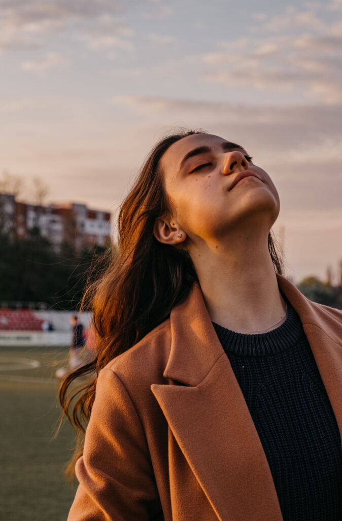 Portrait of a woman enjoying a peaceful moment outdoors during sunset with closed eyes.