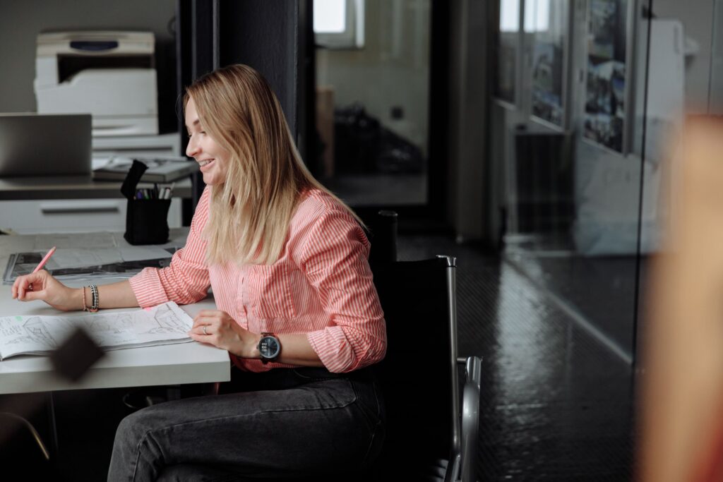 Professional woman sitting at desk working in a bright office setting.