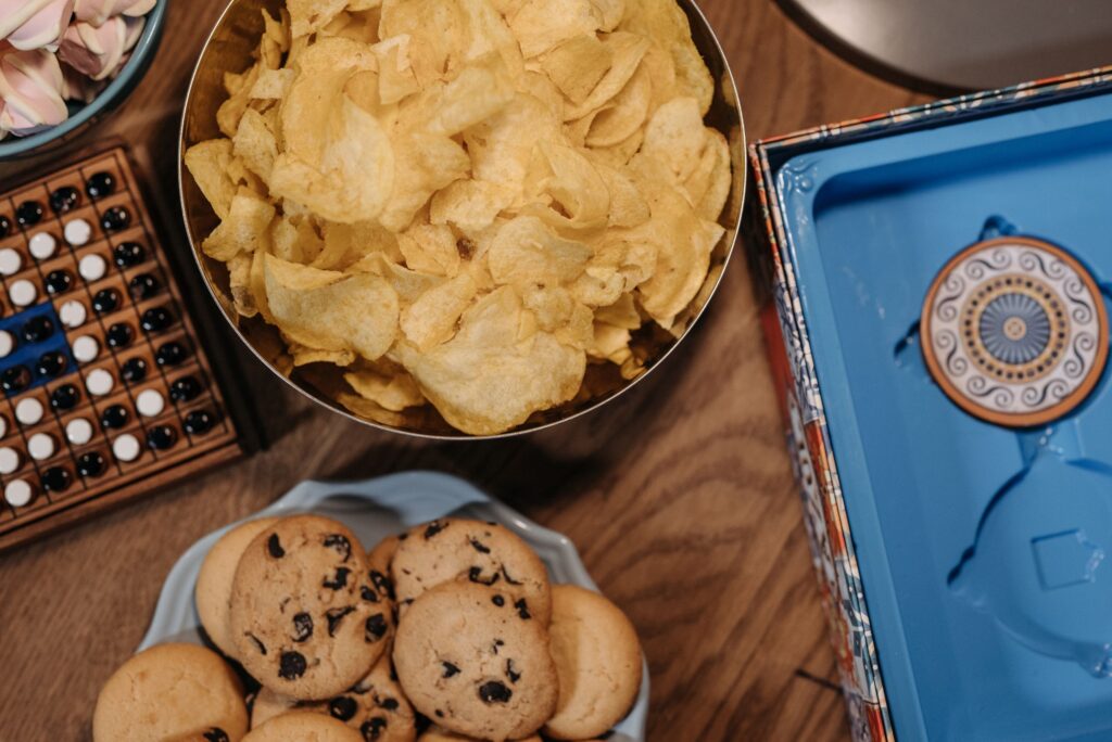 Vibrant snack assortment with chips and cookies on a wooden table.