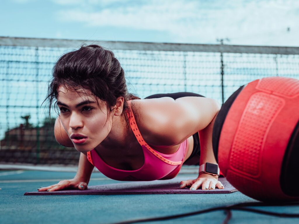 Woman doing push-ups on a sports court in Ji-ParanĂ¡, Brasil, focusing on fitness outdoors.